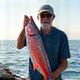 大物を釣り上げて満足げな笑顔を見せるベテラン釣り師の写真